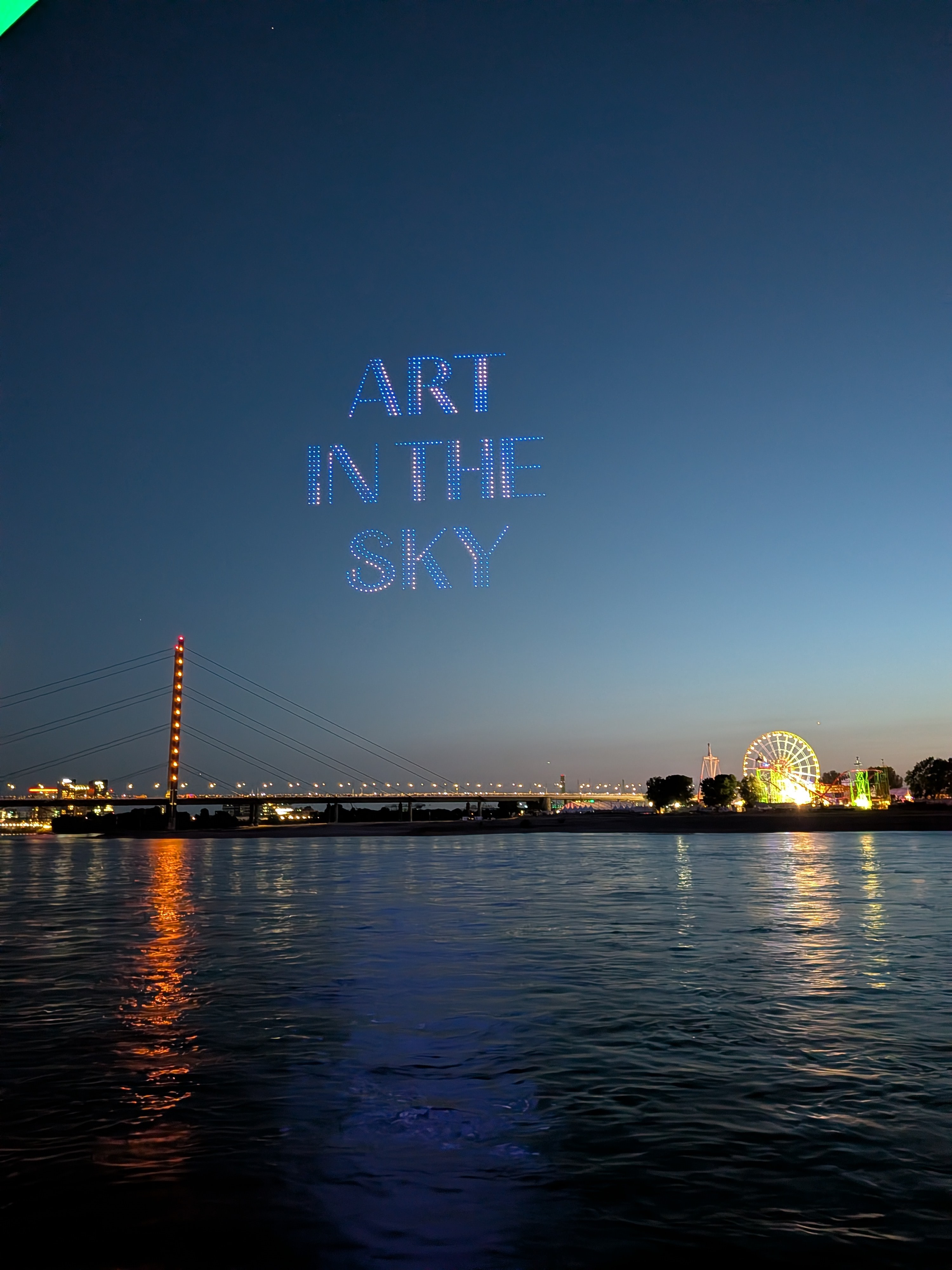 Leuchtender Schriftzug ART IN THE SKY aus Drohnen über dem Rhein, der Rheinkniebrücke und der Rheinkirmes in Düsseldorf