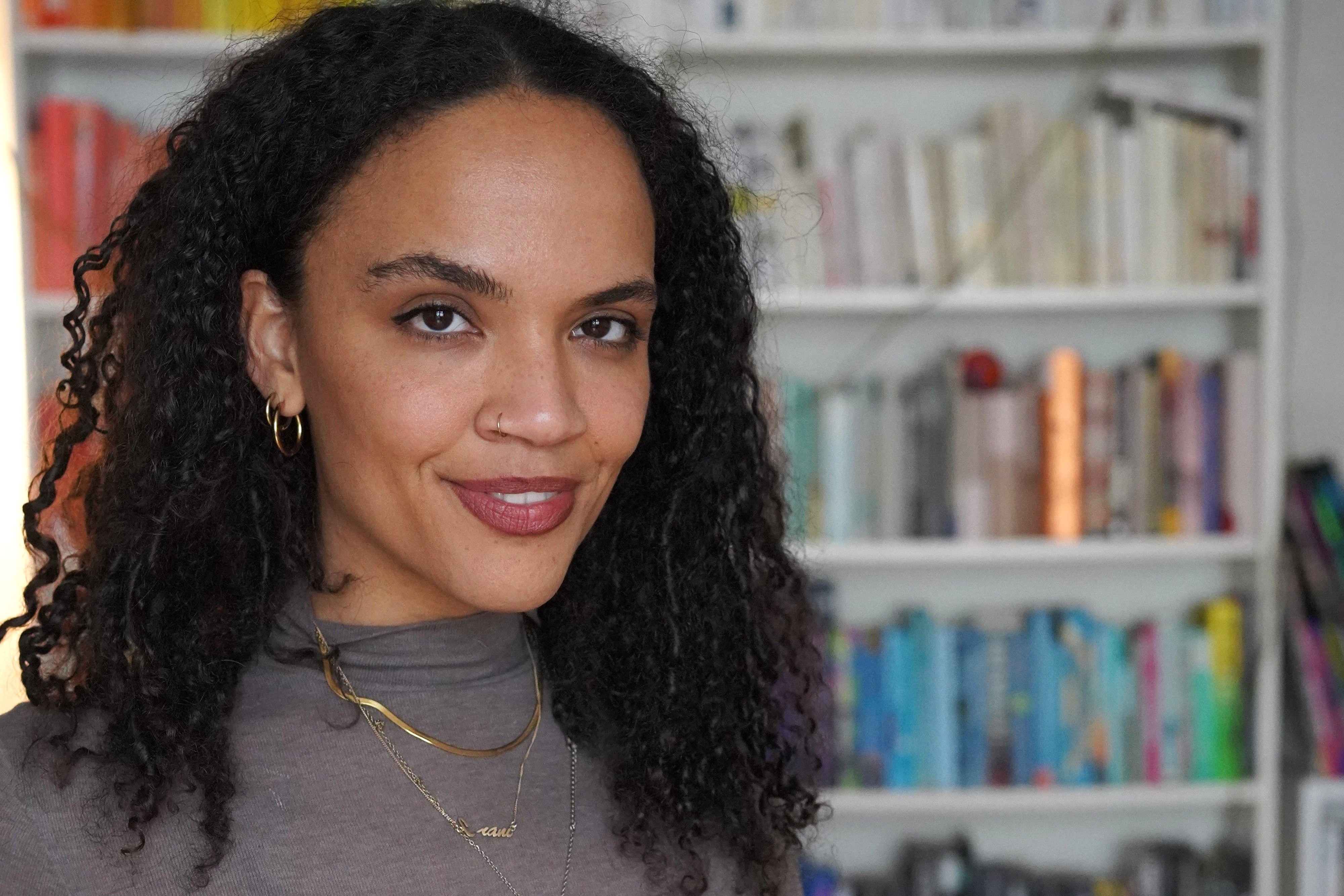 Porträt der Journalistin und Autorin Ciani-Sophia Hoeder vor einem Bücherregal.