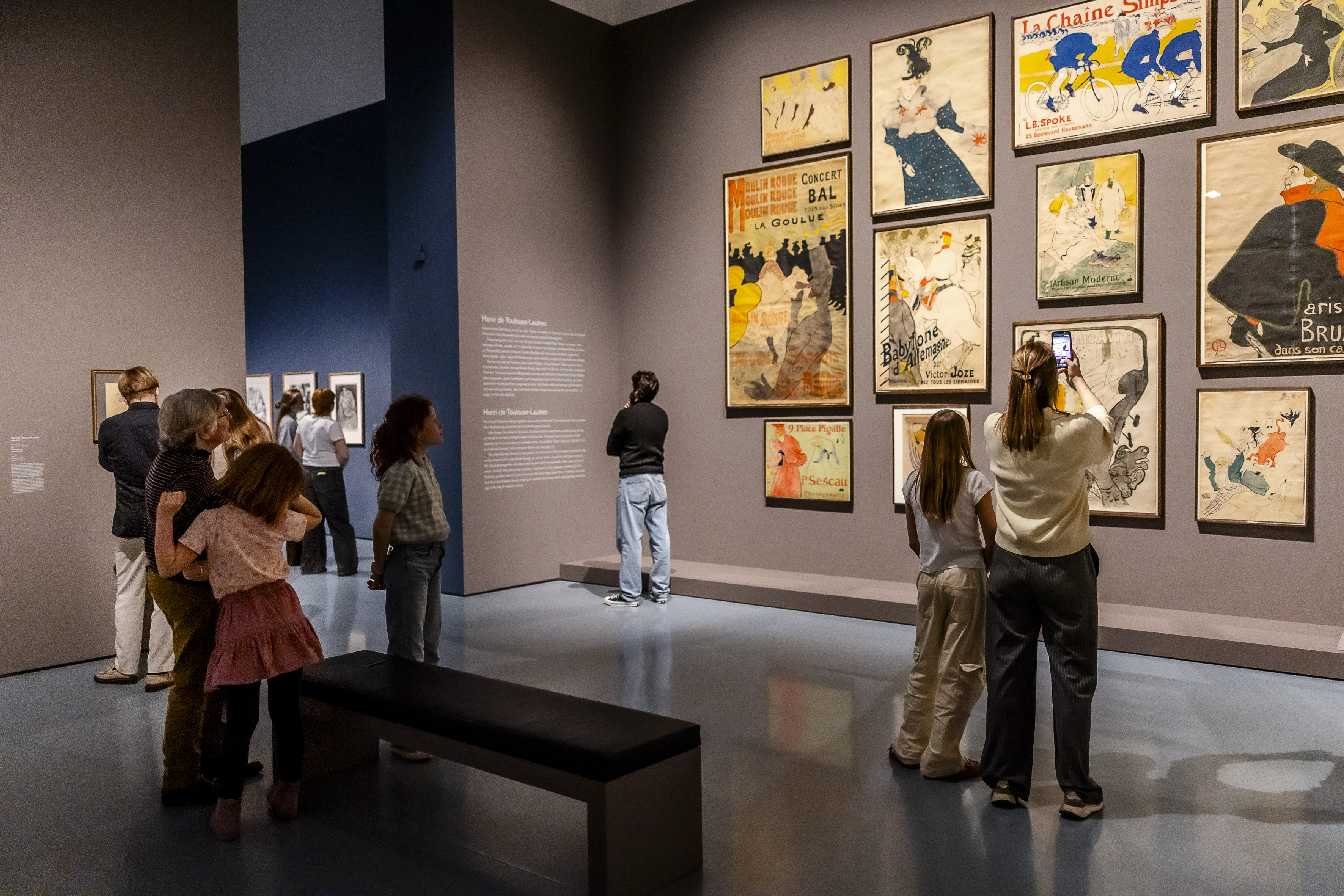 Besucherinnen und Besucher in der Ausstellung „Monet – Cézanne – Matisse. The Scharf Collection“ im Kunstpalast Düsseldorf, vor Plakaten und Werken von Henri de Toulouse-Lautrec.