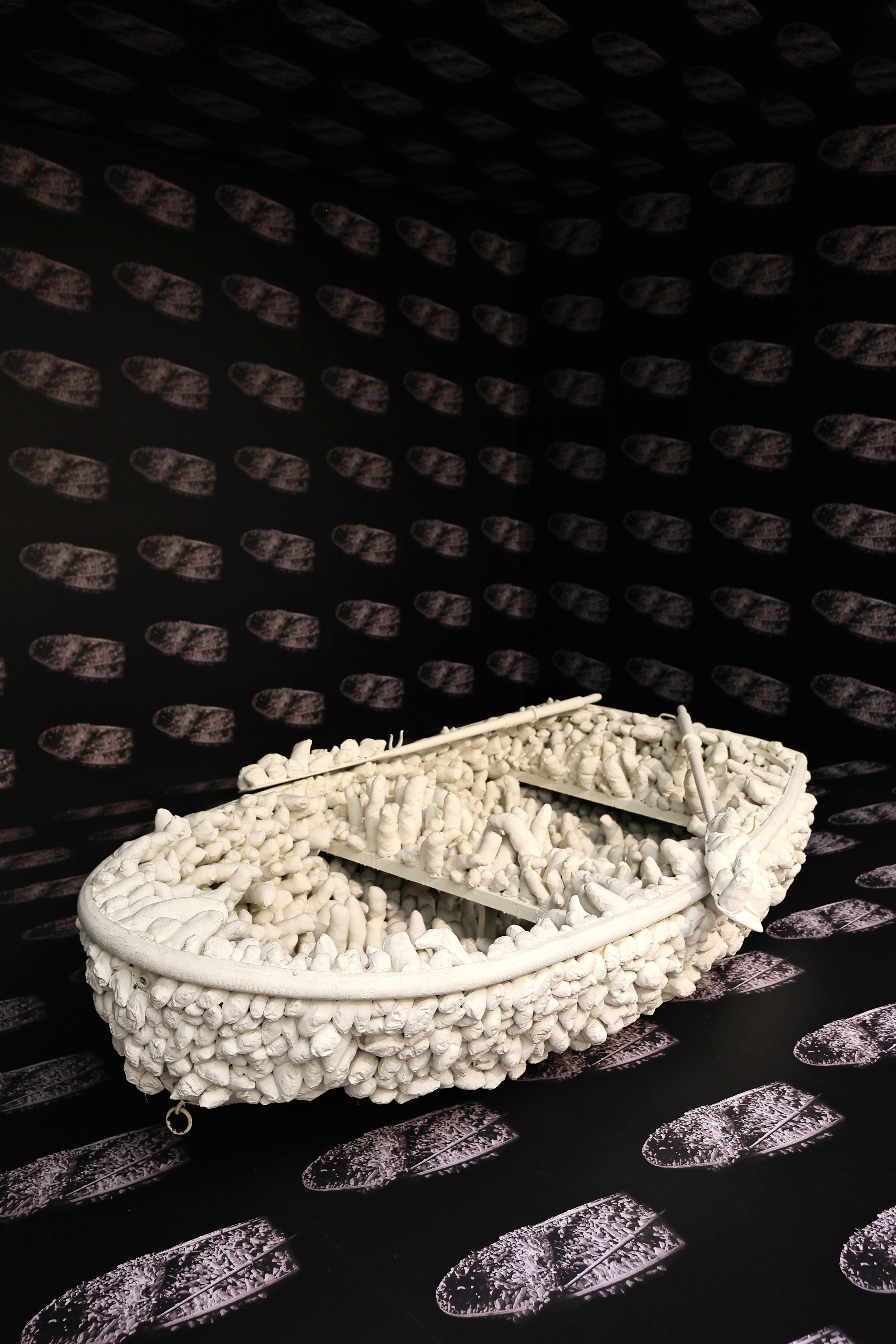 Weißes Boot, dicht bedeckt mit weichen Stoffformen, vor schwarzer Tapete mit wiederholtem Bootsmotiv — Yayoi Kusama, Aggregation: One Thousand Boats Show, 1963, Museum Ludwig Köln