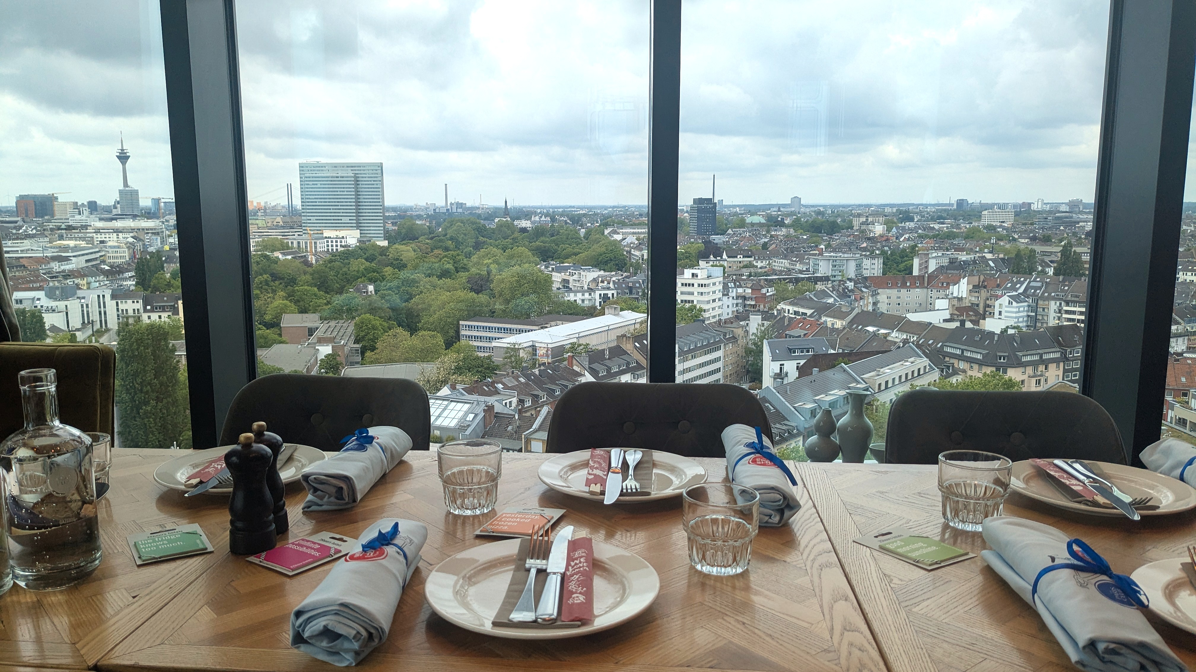 Gedeckter Tisch im The Paris Club mit Blick auf Düsseldorf Gedeckter Tisch mit TAKUMI-Stäbchen und Stoffservietten im The Paris Club, Blick aus der 16. Etage auf die Düsseldorfer Skyline mit Rheinturm