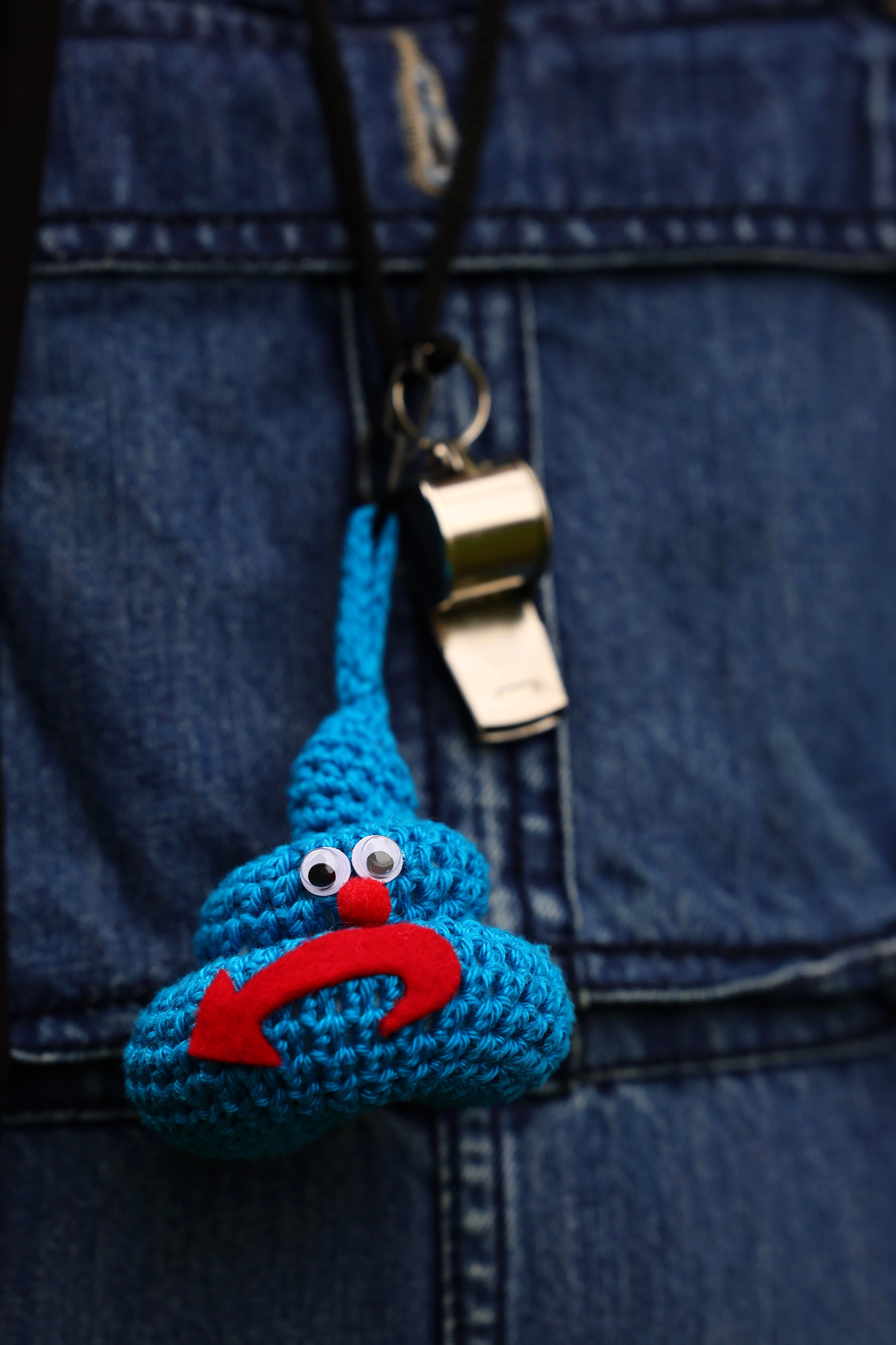 Gehäkeltes blaues Monster mit rotem Pfeil-Symbol und Trillerpfeife an einer Jeansjacke bei der PRÜF-Demo Düsseldorf April 2026