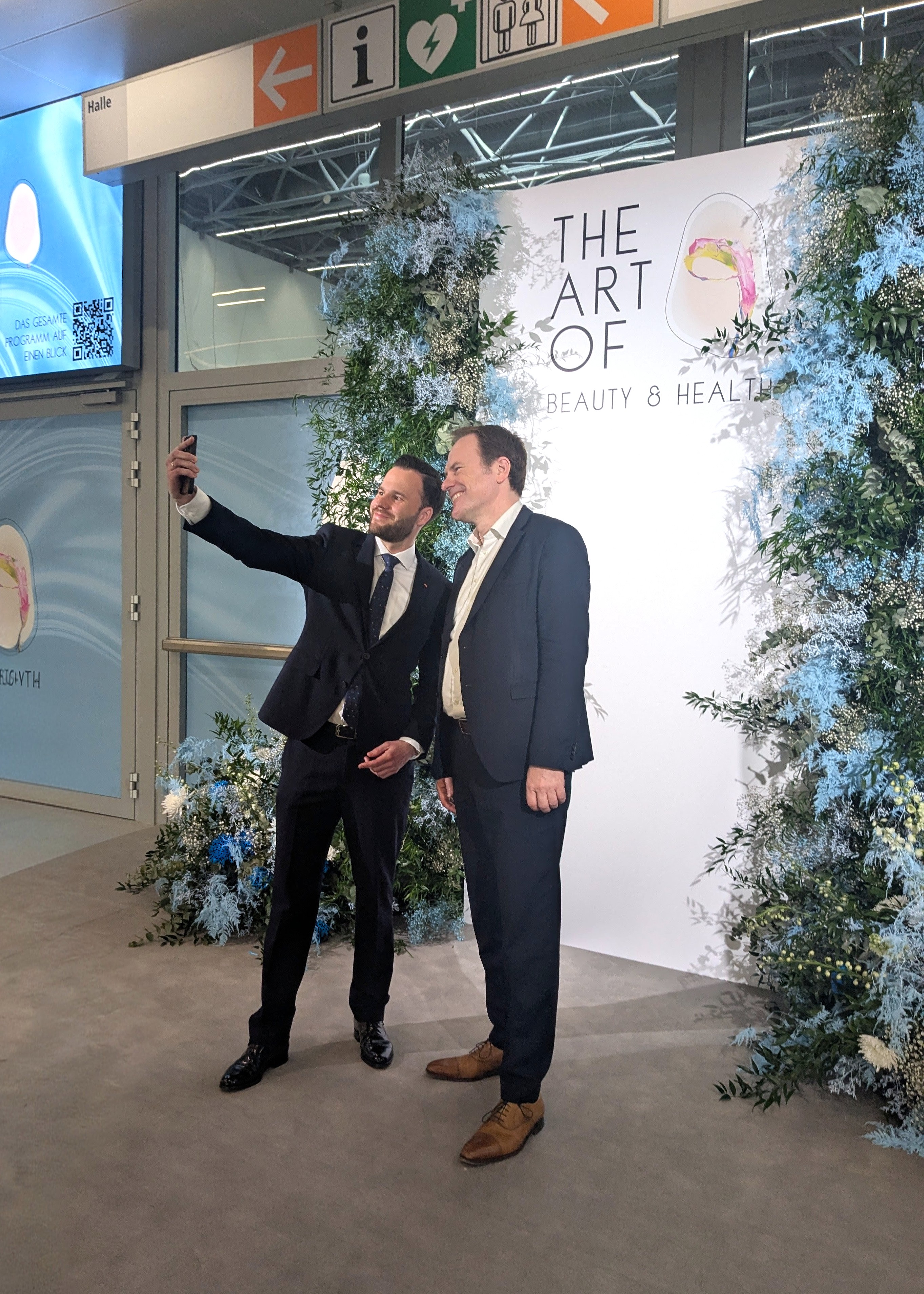 Dr. Stephan Keller und Marius Berlemann beim Selfie vor dem floralen Portal, The Art of Beauty & Health, Messe Düsseldorf 2026